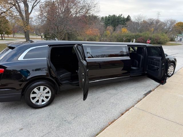 Black stretch limousine parked on a street with both rear side doors open.