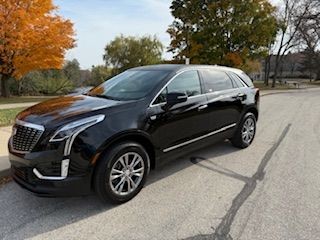 Black SUV parked on a suburban street with autumn trees in the background.